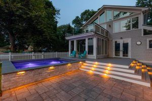 Illuminated pool and deck in front of home