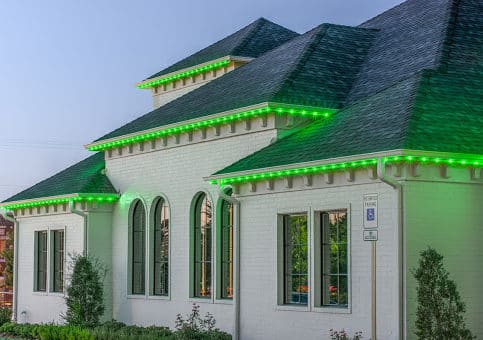 Bright green christmas lights hanging about roofs edge