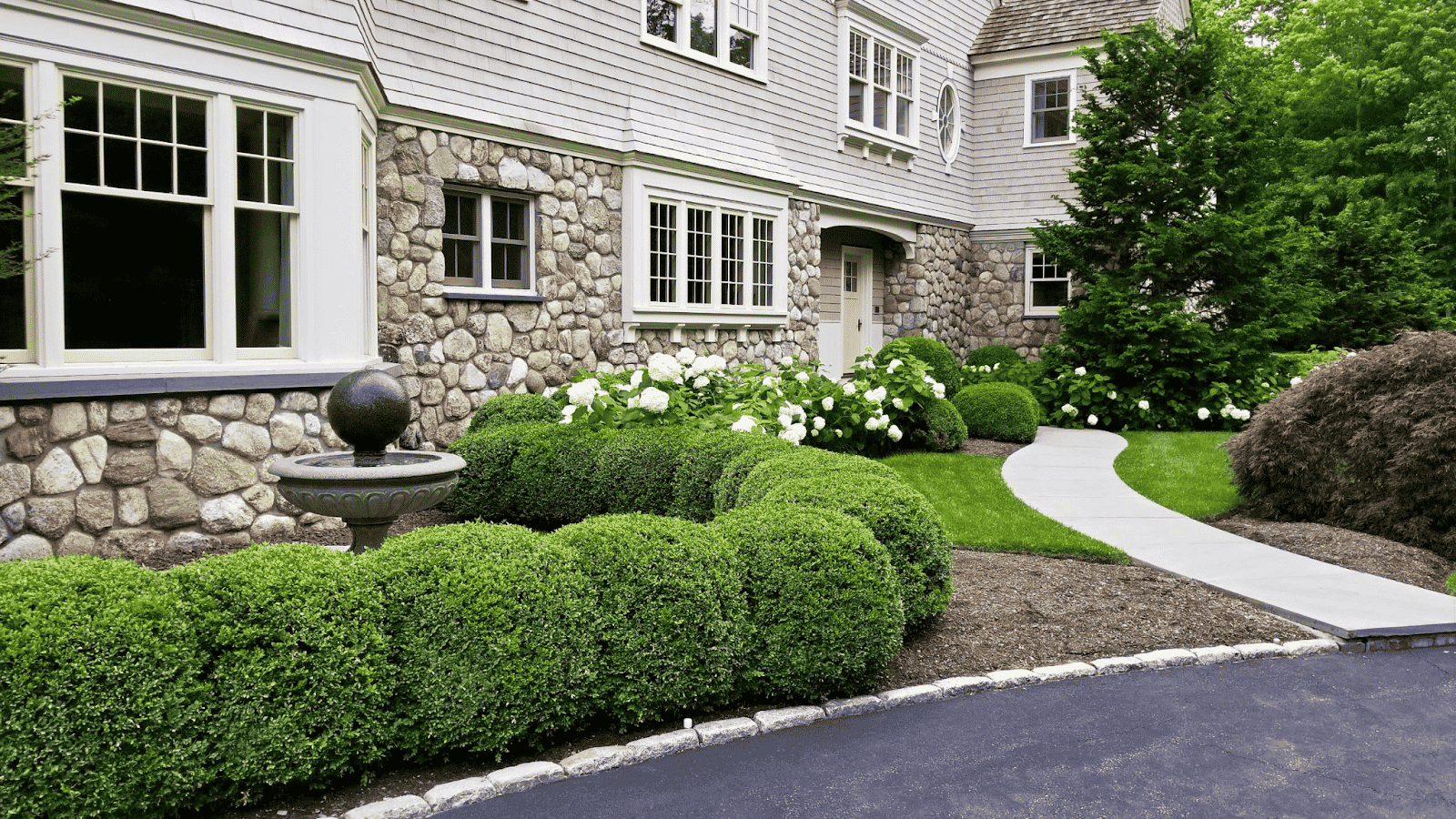 Side view of mansion, shrubs, landscaping