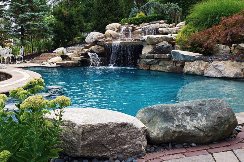 Elegant pool with rock features and waterfalls answers the question does luxury swimming pool add value to home