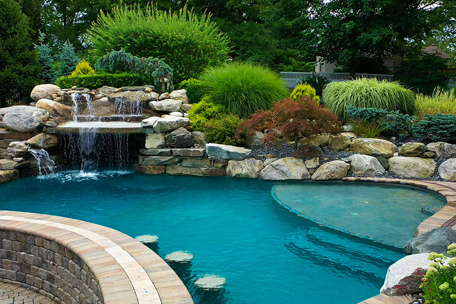 Exquisite premier pool with sun shelf installation, embraced by vibrant plants and lush greenery