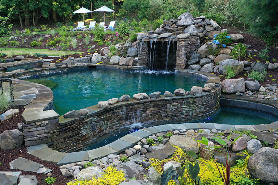 Serene pool featuring a water grotto, nestled within lush landscapes and natural surroundings